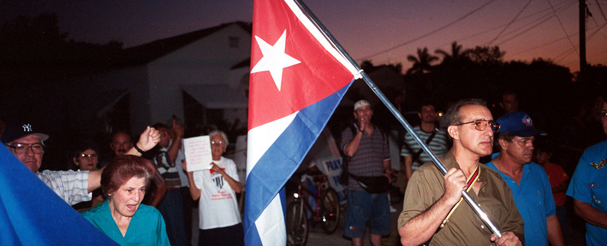 Cuban protestors, with one man in the front holding up the Cuban flag. 